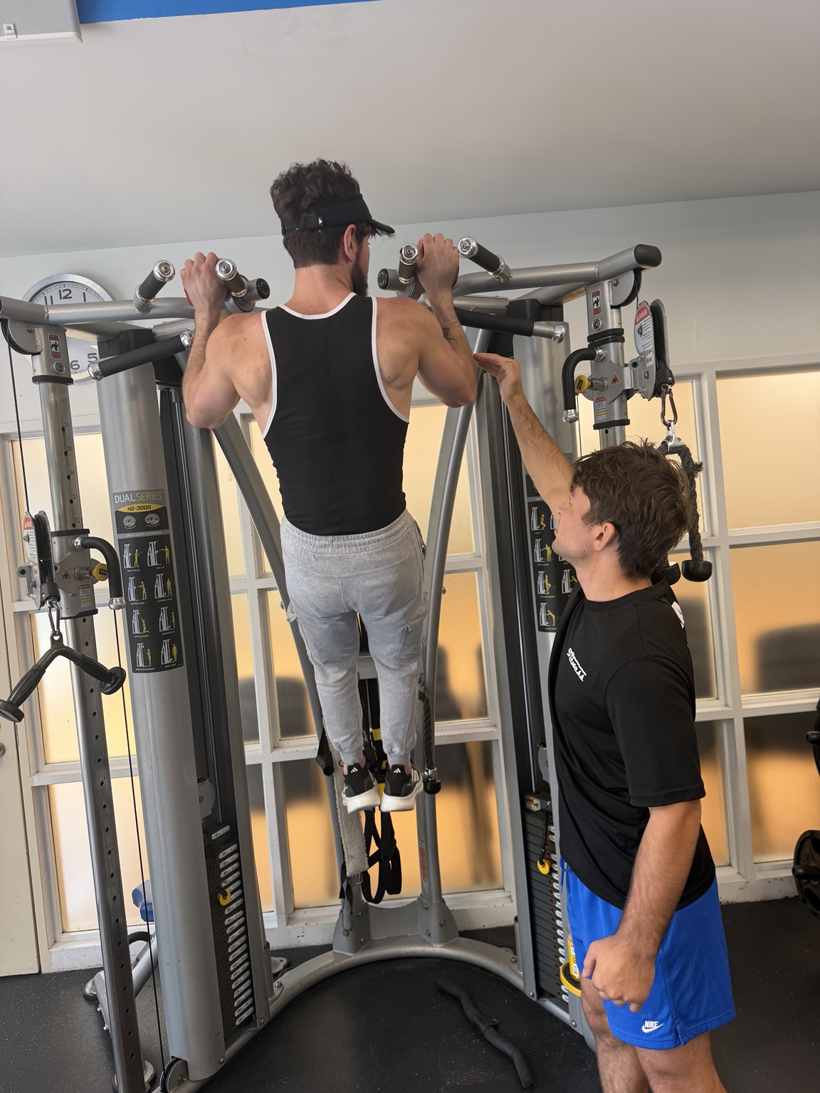 A PHI coach guiding a client through a pull-up